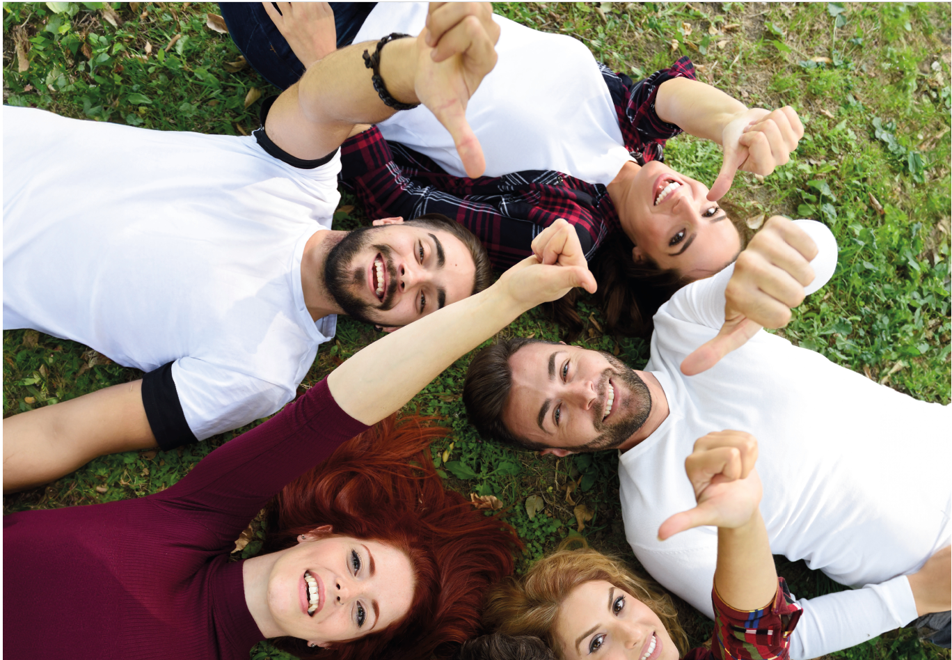 ludzie leżacy na trawie z kciukami do góry