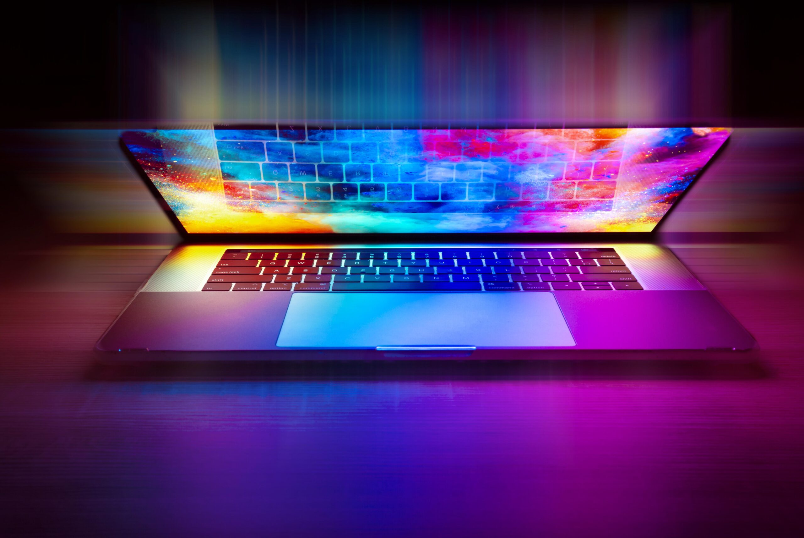 otwarty laptop z kolorowym ekranem z wrażeniem świateł wychodzacych w przestrzeń